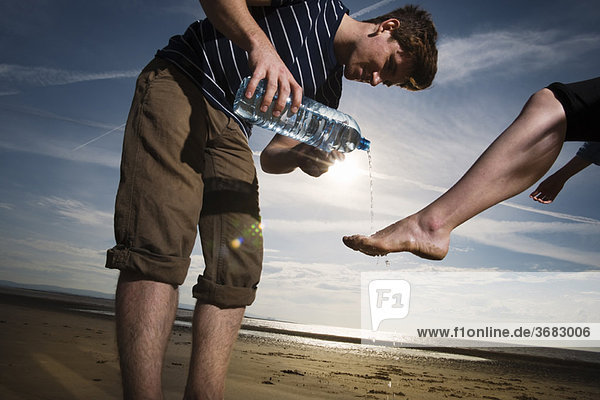 Mann wäscht Frauenfüße am Strand