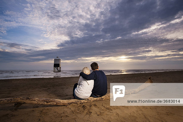 Paar beobachtet Sonnenuntergang am Strand