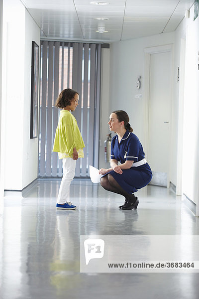 Krankenschwester im Gespräch mit Kind im Flur