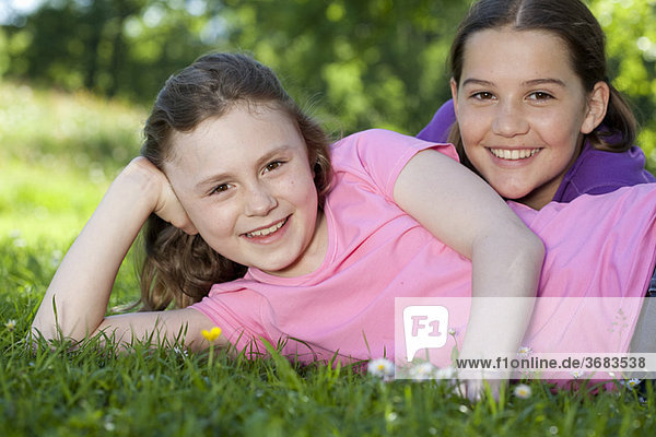 Zwei Mädchen  die sich auf der Wiese ausruhen  glücklich.