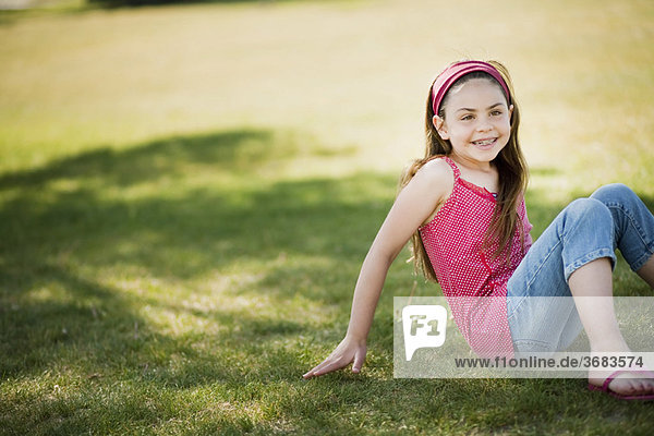 Junges Mädchen auf Gras sitzend lachend