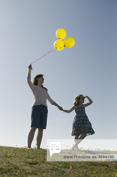Frau und Kind mit Ballons auf dem Hügel