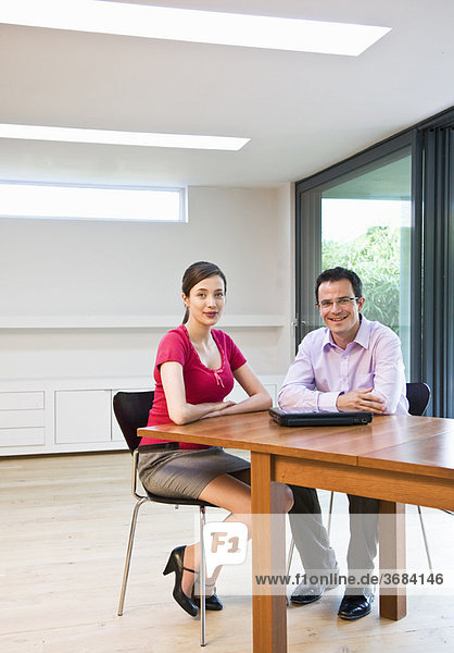 Confident man & woman in modern office
