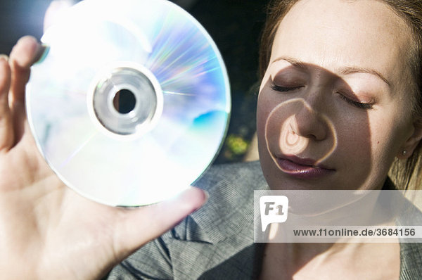 Frau hält DVD der Sonne entgegen