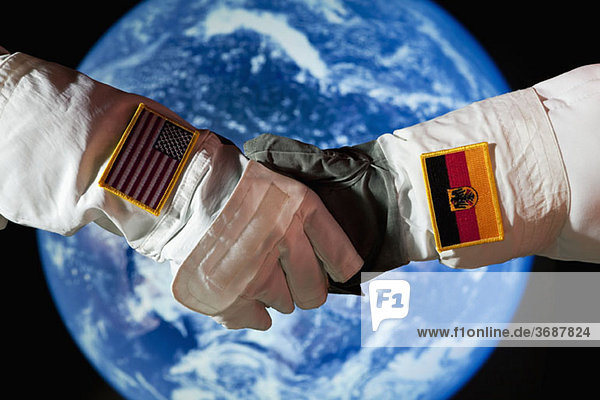 Ein amerikanischer Astronaut  der einem deutschen Astronauten die Hand schüttelt.