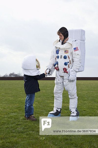 Ein Junge mit einem Weltraumhelm  der einem Astronauten die Hand schüttelt.