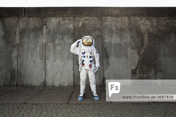 Ein salutierender Astronaut  der auf einem Bürgersteig in einer Stadt steht.