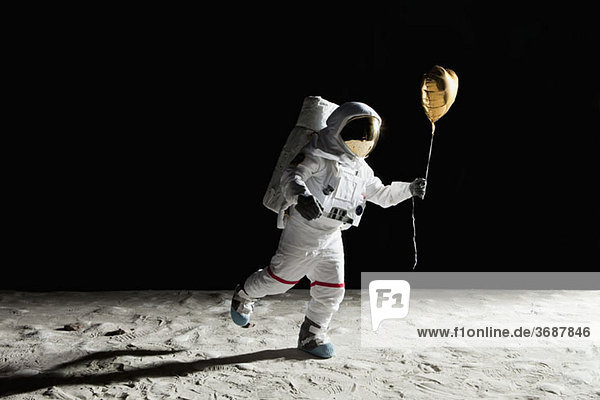 Ein Astronaut auf dem Mond hält einen herzförmigen Heliumballon.