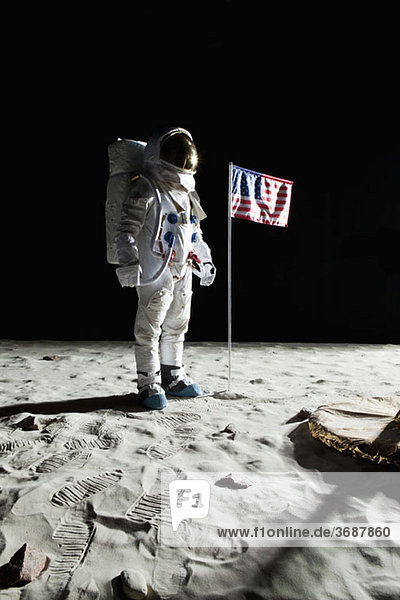 Ein Astronaut auf dem Mond steht neben einer amerikanischen Flagge.