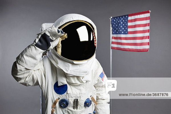 Ein Astronaut salutiert neben einer amerikanischen Flagge  Studioaufnahme