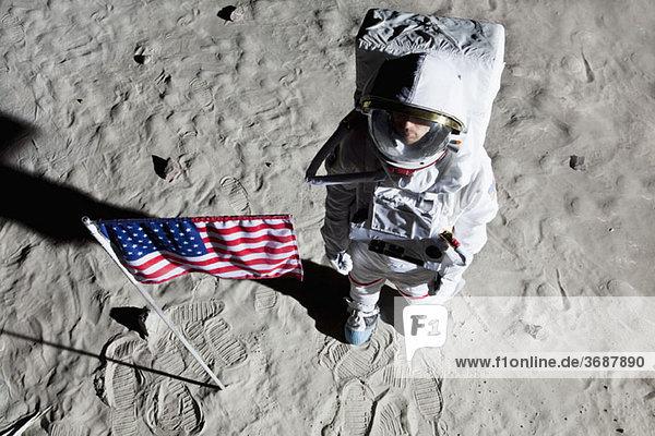 Ein Astronaut auf der Mondoberfläche neben einer amerikanischen Flagge