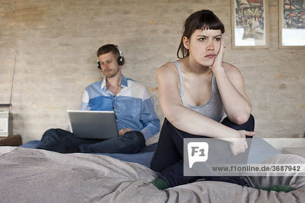 Ein Mann  der einen Laptop benutzt und seine frustrierte Freundin ignoriert.