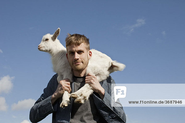 A man carrying a kid goat on his shoulders