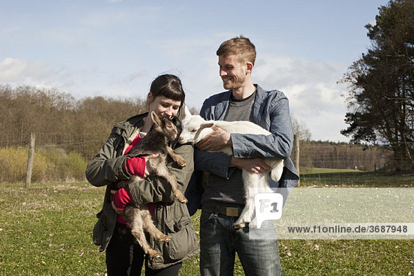 A couple holding kid goats