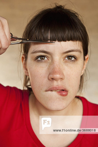A woman trimming her own bangs