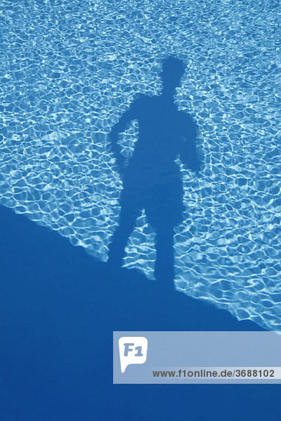 Schatten eines Mannes am Rande eines Swimmingpools