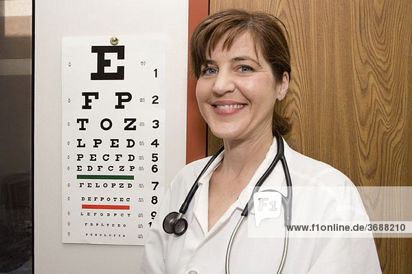 Ein Arzt steht vor einem Augendiagramm und lächelt.