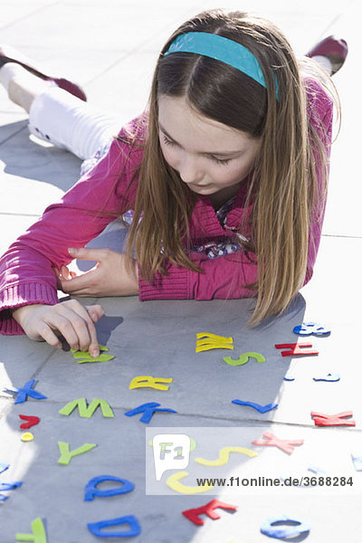 Ein Mädchen spielt mit Filzalphabetbuchstaben