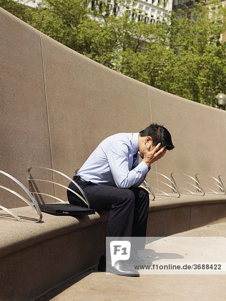A distraught businessman with his head in hands