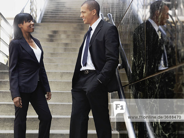 A businesswoman talking with a businessman outside of an office building