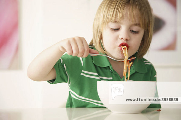 Ein Junge  der Spaghetti isst.