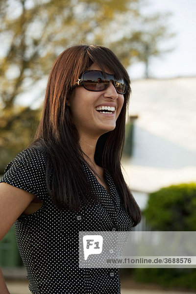 Porträt einer jungen Frau mit Sonnenbrille und Lachen