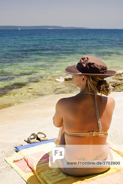 Frau mit Hut sitzt am Meer  Insel Ugljan  Zadar  Dalmatien  Kroatien  Europa