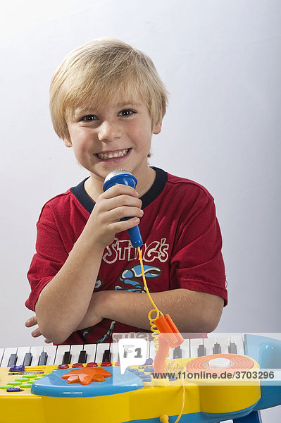 Boy  4-5 years  playing on a colorful toy piano and singing into a microphone