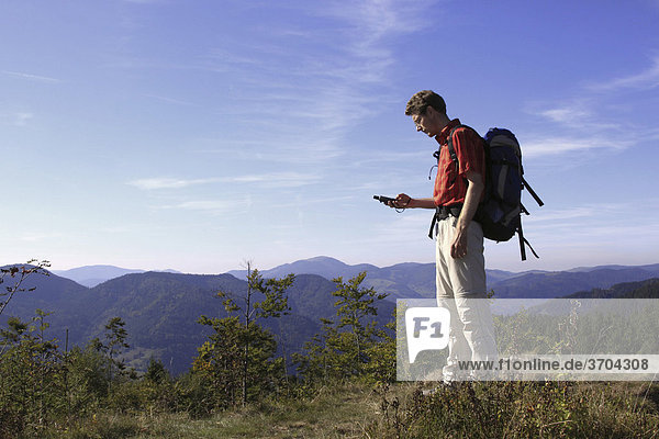 Geocacher checking the coordinates with a GPS navigation system on Mt. Leder Tschobenstein in Bernau in the Black Forest  Baden-Wuerttemberg  Germany  Europe