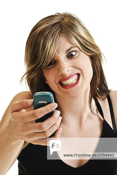 Young woman with an angry expression holding a cellphone in her hand