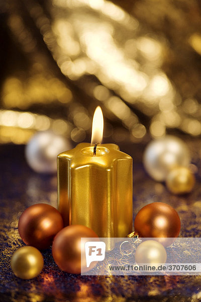 Burning golden candle with baubles for the Christmas tree