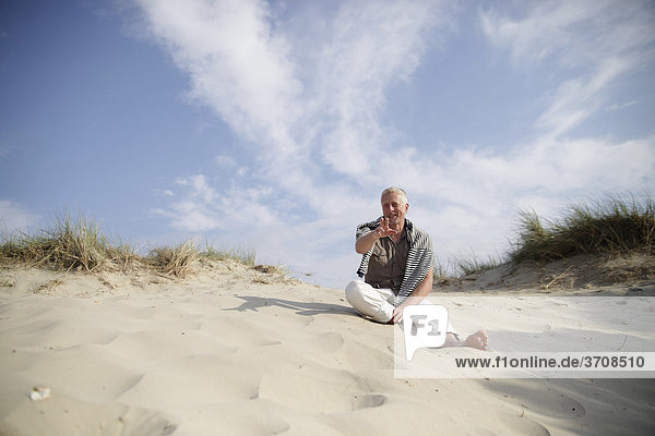 Male Best Ager sitting in the dunes at the North Sea in De Haan  Belgium  Europe