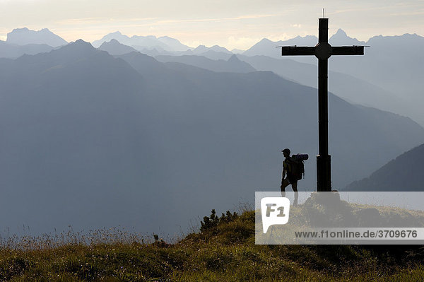 Mountain climber standing beside a summit cross  Gaschurn  Montafon  Vorarlberg  Austria  Europe