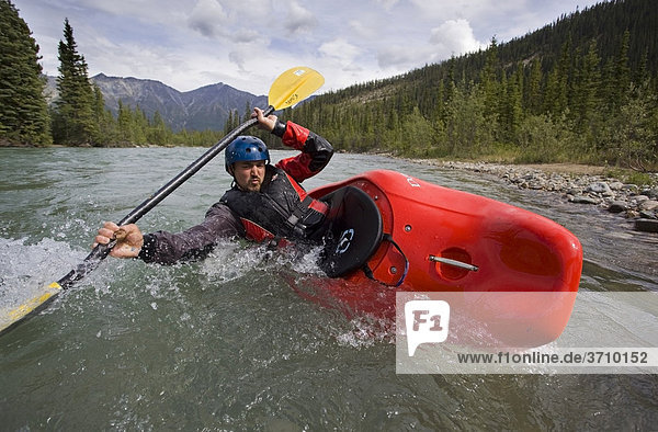 White water kayaking  man paddling a play boat  stabilizing boat  high brace  mountains  coastal range behind  Wheaton River  Yukon Territory  Canada