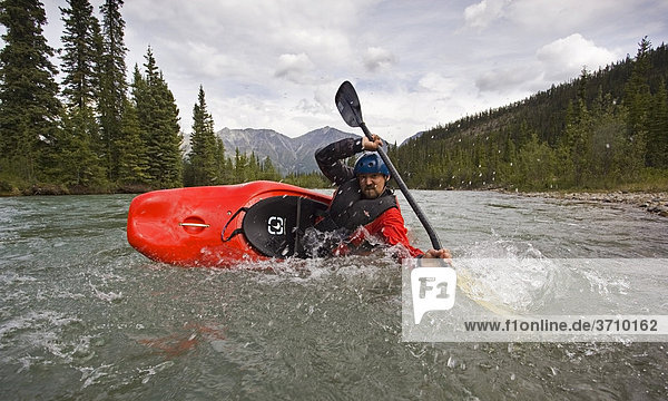 White water kayaking  man paddling a play boat  stabilizing boat  high brace  mountains  coastal range behind  Wheaton River  Yukon Territory  Canada