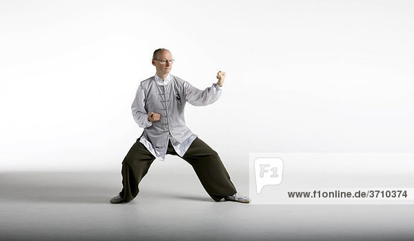 Taiji Meister in klassischer Taiji Bewegung  Chansi Gong  in chinesischem Taiji-Anzug