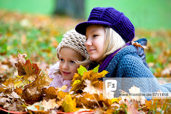 Two girls  sisters  in a park in autumn