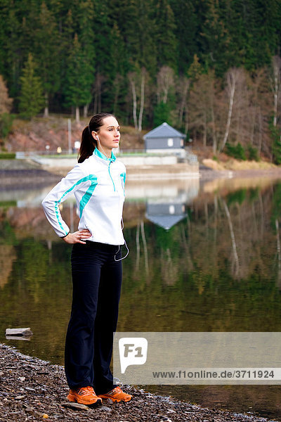 Junge Frau wärmt sich auf für Jogging am Waldsee