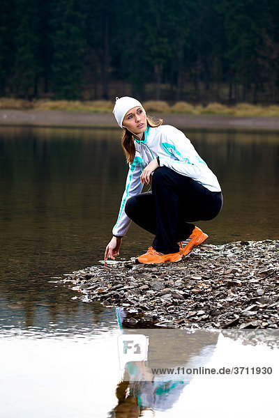Junge Frau macht beim Joggen Pause am Waldsee