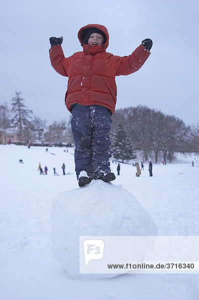 Boy standing on big snow ball