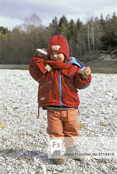Little two year old boy with stones in his hand at the Isar Publinger Au