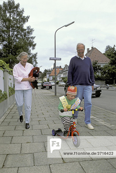 Grand parents are walking with their two year old grandson on the day of his birthday