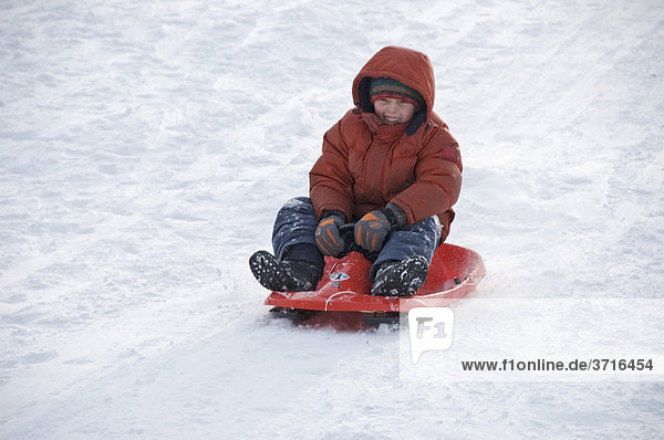 A child is sledging down a hilll