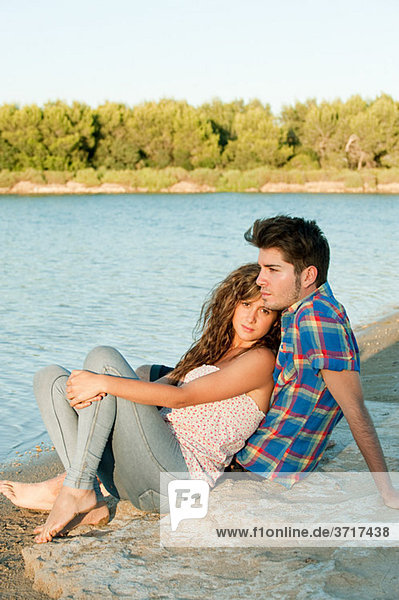 Young couple sitting near lake