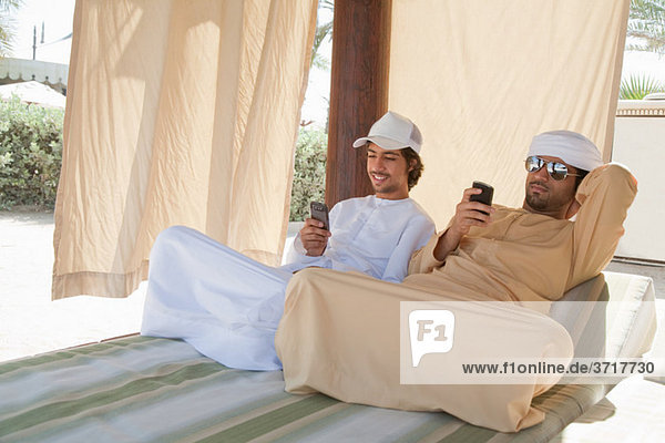 Zwei Nahen Ostens Männer sitzen auf dem Bett