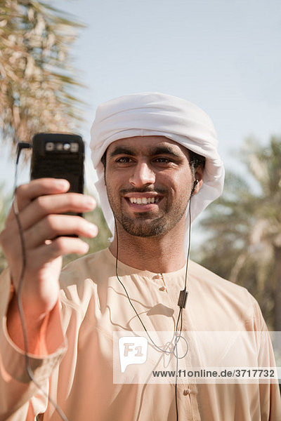 Mann aus dem Nahen Osten hört Musik auf dem Handy