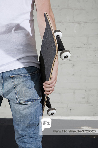 Skateboarder hält sein Brett in der Hand