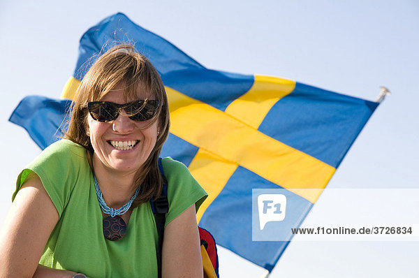 Lachende junge Frau vor Schwedenflagge