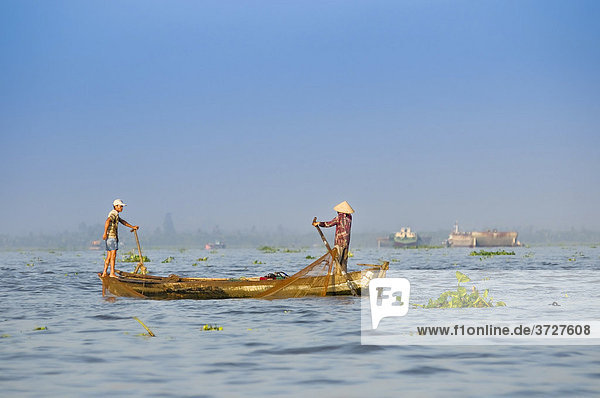 Zwei Fischer  Mann und Frau mit traditionellem vietnamesischen Kegelhut rudern ein Boot am Mekong  Vinh Long  Mekongdelta  Vietnam  Asien