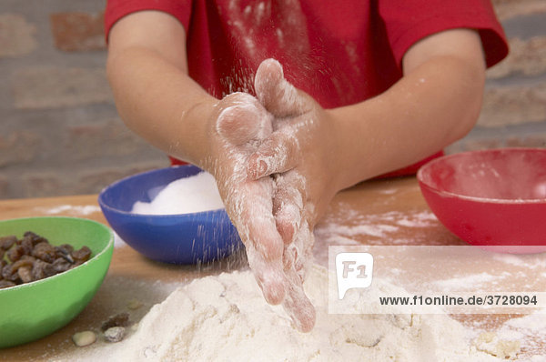Kinderhände beim Backen mit Mehl